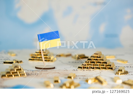 Ukrainian flag with mini gold bars on a detailed map represents national wealth, economic resilience, and strategic resource control amidst global challenges 127169025