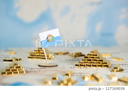 San Marino flag on global map beside shining gold bar pyramids, symbolizing national economic prosperity, financial investment, wealth, and global trade, with copy space 127169036