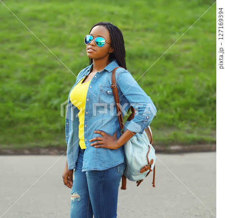 Portrait of stylish young African woman student with backpack, black girl outdoors in summer park Portrait of stylish young African woman student with backpack, black girl outdoors in summer park 127169394