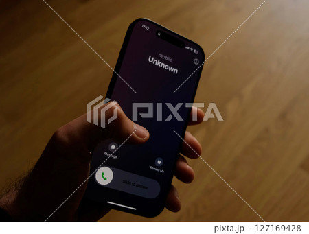 Fraud or fraudulent schemes. Close-up of a male hand holding a phone with an unexpected incoming call from an unknown Fraud or fraudulent schemes. Close-up of a male hand holding a phone with an unexpected incoming call from an unknown 127169428