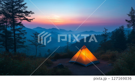 紫の夕暮れに包まれた山岳地帯と灯りのともるソロキャンプのテント 127169836