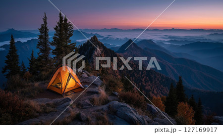 山頂で夕暮れを迎えるオレンジ色のテントと広がる山並みの絶景 127169917