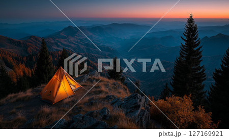 山頂で夕暮れを迎えるオレンジ色のテントと広がる山並みの絶景 127169921
