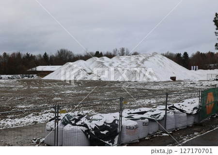 Large pile of snow sits in front of a fence 127170701