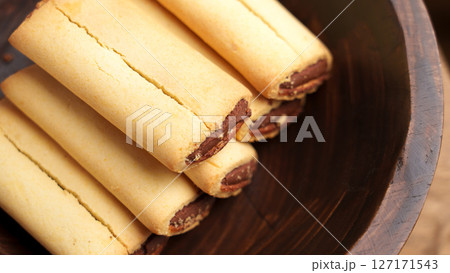 Sweet fig bar cookies with chocolate filling in wooden brown bowl. Macro shot. Sweet fig bar cookies with chocolate filling in wooden brown bowl. Macro shot. 127171543