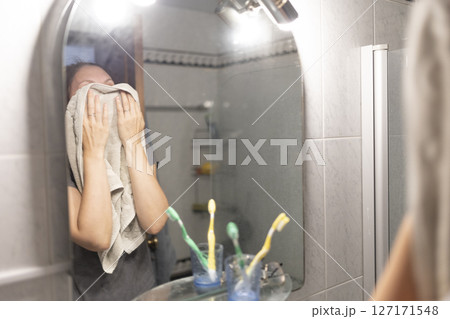 Woman drying face with towel after hot shower in bathroom 127171548