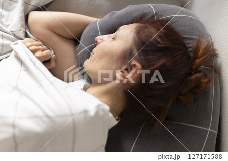 Woman sleeping peacefully in bed on gray pillow 127171588