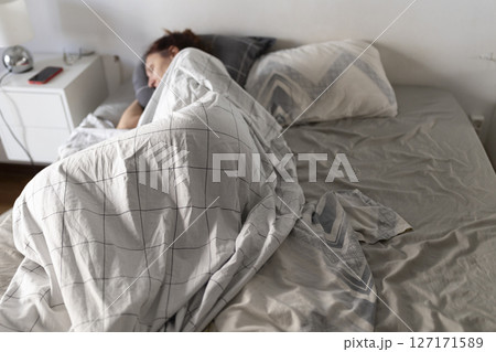 Woman sleeping peacefully in bed covered by checkered blanket Woman sleeping peacefully in bed covered by checkered blanket 127171589