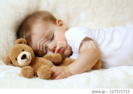 Little boy sleeping sweetly on a white bed, holding his soft teddy bear. Peaceful nap time at home, symbolizing comfort, innocence, warmth, and childhood dreams in cozy and quiet atmosphere. 127171715