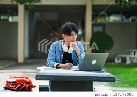College student studying on campus outdoor with laptop casual lifestyle. College student studying on campus outdoor with laptop casual lifestyle. 127172006
