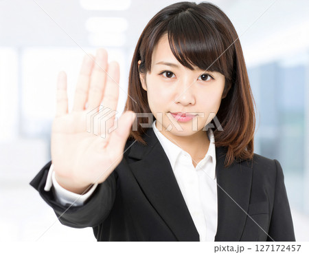 拒否するように手を前に出している若い会社員の女性 127172457