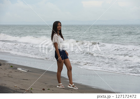 Confident woman standing on beach near sea waves Confident woman standing on beach near sea waves 127172472