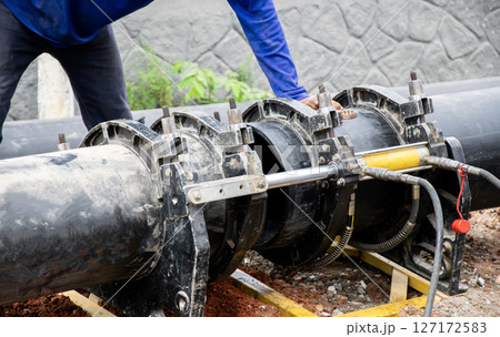 The technician is welding pipes with a hydraulic press. 127172583