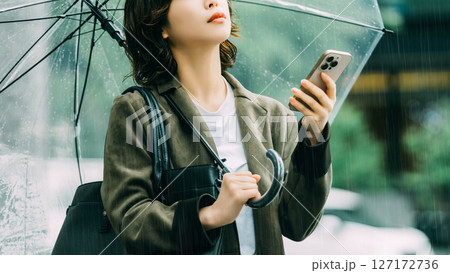 傘をさしてスマホを使う女性（梅雨・6月） 127172736