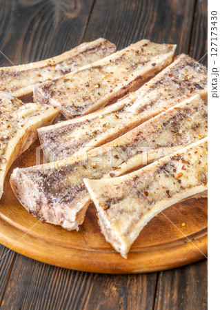 Rustic roasted marrow bones rest on warm wooden board, savory richness revealed Rustic roasted marrow bones rest on warm wooden board, savory richness revealed 127173430