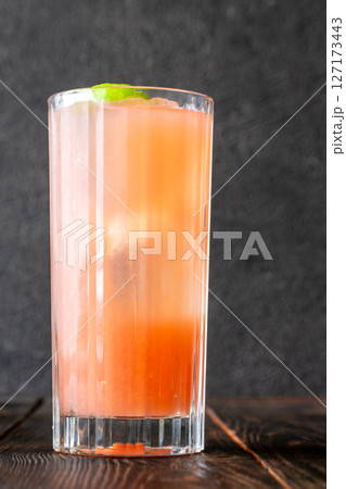 Guava Collins cocktail sparkles in tall glass with lime against dark backdrop Guava Collins cocktail sparkles in tall glass with lime against dark backdrop 127173443