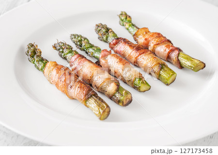 Crispy Fried Asparagus Wrapped In Bacon Served Simply On White Plate 127173458