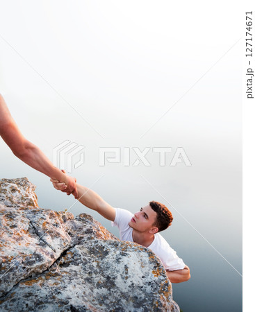 Man help his friend to climb on the rock 127174671