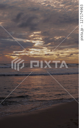 Dramatic Ocean Sunset with Colorful Clouds and Gentle Waves on a Tranquil Evening Beach Dramatic Ocean Sunset with Colorful Clouds and Gentle Waves on a Tranquil Evening Beach 127174963
