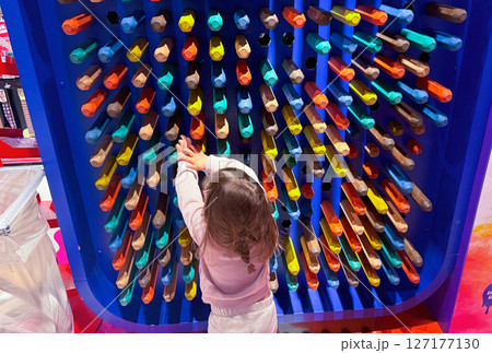 Background with large wooden colored crayon wall and a little girl with brown hair 127177130