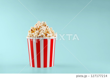 Classic red striped popcorn cardboard cup on blue background 127177214