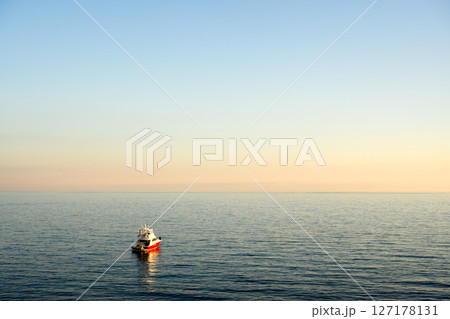 Evening coastal scene with lonely fishing boat 127178131