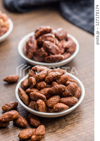 Almond nuts coated in sugar and honey in bowl on wooden table. Almond nuts coated in sugar and honey in bowl on wooden table. 127178174