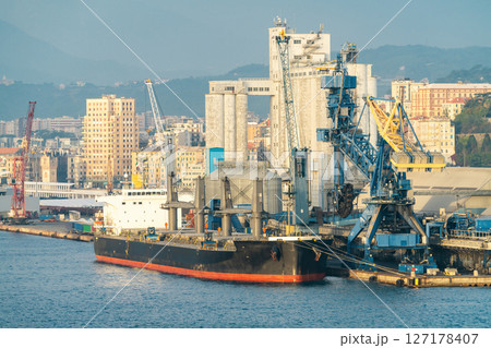 Bulk carrier at industrial port with cranes and city skyline, Savona Bulk carrier at industrial port with cranes and city skyline, Savona 127178407