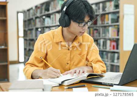Young collage student using computer and mobile device studying online. 127178565