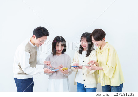 スマートフォンを見せながら使う親子　白バック 127181235