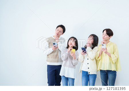 考え事をしながらスマートフォンを使う親子 白バック 考え事をしながらスマートフォンを使う親子 白バック 127181395