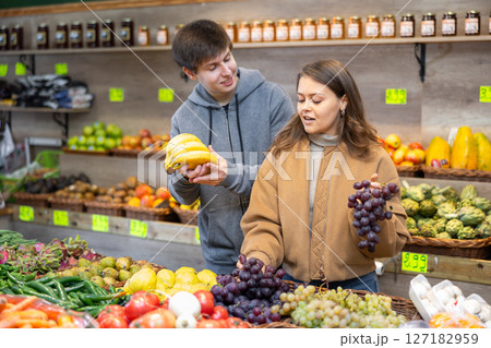 Young woman and young guy choose grapes and bananas Young woman and young guy choose grapes and bananas 127182959