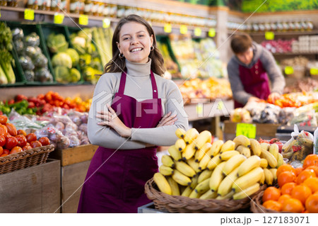 Young woman seller laying out bananas on counter 127183071