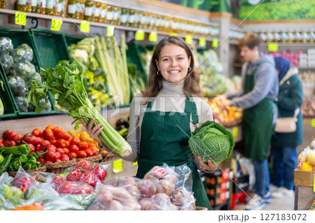 Young woman seller lays out cabbage and celery 127183072
