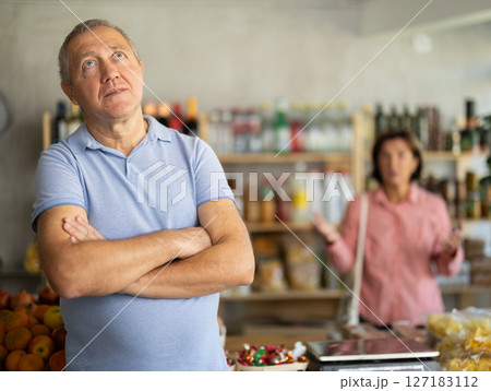 Senior wife stands behind pensioner husband and yells at companion. Senior wife stands behind pensioner husband and yells at companion. 127183112