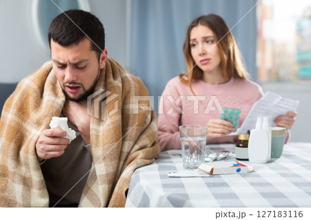 Ill man sitting at table near his wife who helping him with medicine 127183116