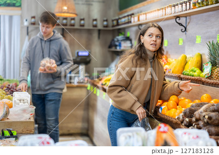Young woman choosing tangerines in vegetable shop 127183128