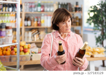 Mature woman choosing beer in grocery store 127183129