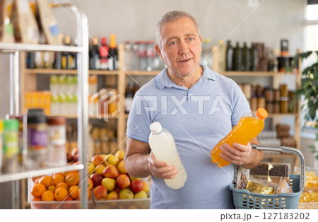 Mature man is choosing natural juice in grocery store 127183202