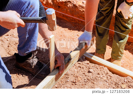 Construction workers secure wooden supports while working diligently at construction site Construction workers secure wooden supports while working diligently at construction site 127183208