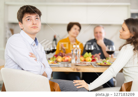 Dissatisfied guy turned away from the festive table, where his family and friends were having conversation. Quarrel during home dinner 127183209