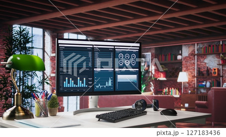 Desktop PC on the wooden desk showcases infographics and client reach data for professional use, analytics on display. Stylish, organized workspace in a bright luxurious loft home. 127183436