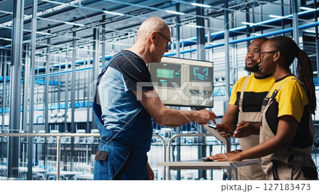 Experienced team leader doing induction to new trainees in industry 4.0 photovoltaics plant. Senior engineer in smart solar panels factory teaching interns to maximize power generation, camera A Experienced team leader doing induction to new trainees in industry 4.0 photovoltaics plant. Senior engineer in smart solar panels factory teaching interns to maximize power generation, camera A 127183473