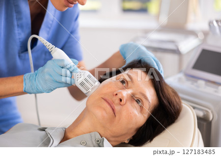 Mature woman receiving hardware facial procedure using cooling attachment 127183485