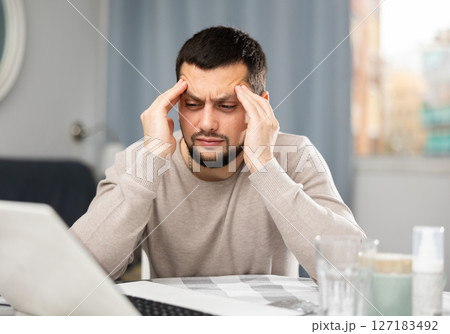 Man suffering from headache after studying at home on laptop 127183492