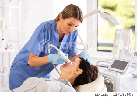 Woman doctor doing facial deep hydration procedure on elderly female pacient in aesthetic medicine clinic 127183605