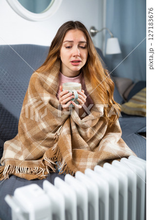 Adult woman with cup near heater in home closeup 127183676