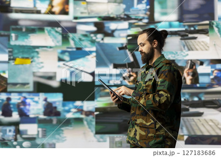 Armed forces soldier gathers surveillance from digital drone systems, preparing for combat with warfare strategies and battlefield details. War planning operations in command center. 127183686