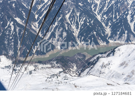 立山ロープウェイの黒部平駅付近から見下ろす黒部ダムと雪に覆われた雄大な山々の美しい冬景色 127184681