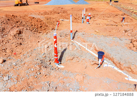 Construction workers are installing plumbing at residential site while earthwork continues Construction workers are installing plumbing at residential site while earthwork continues 127184888